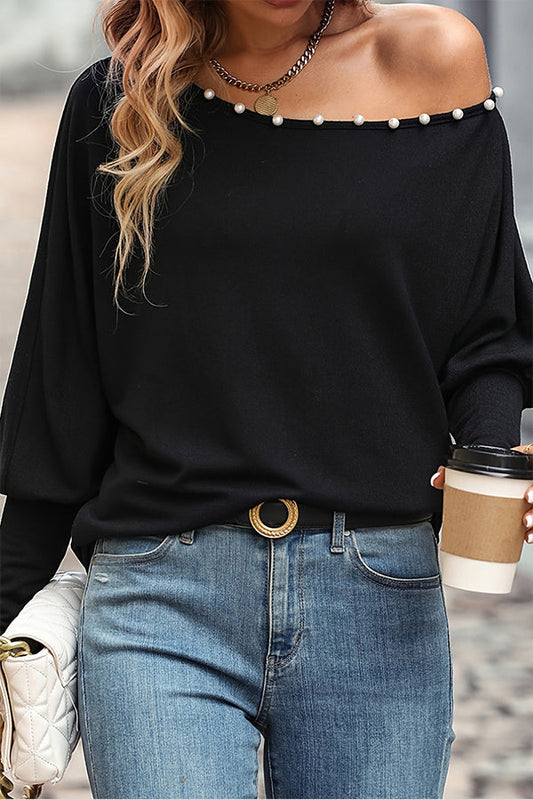 Blusa con cuello asimétrico y mangas abullonadas de perlas negras
